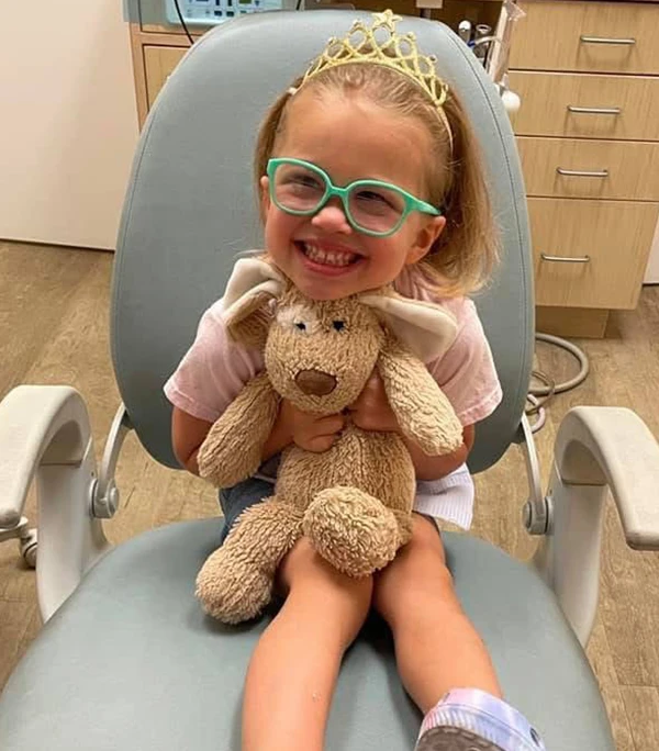 A toddler holding her stuffy and smiling at the camera