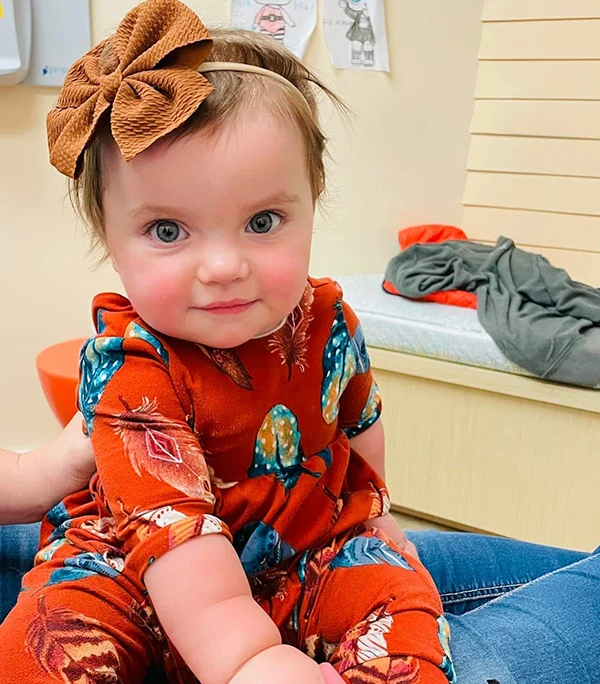 An infant in her mother's lap at Howell Pediatric Dentistry