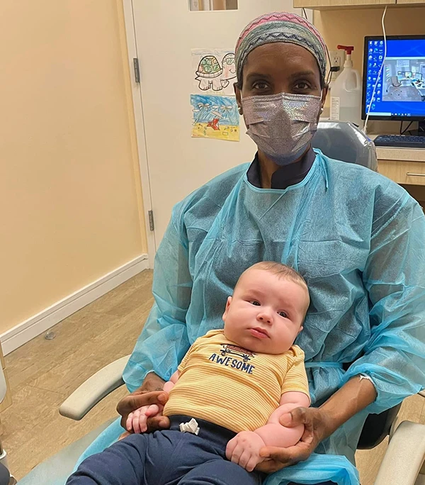 An infant sitting in Dr. Karan's lap during first visit.
