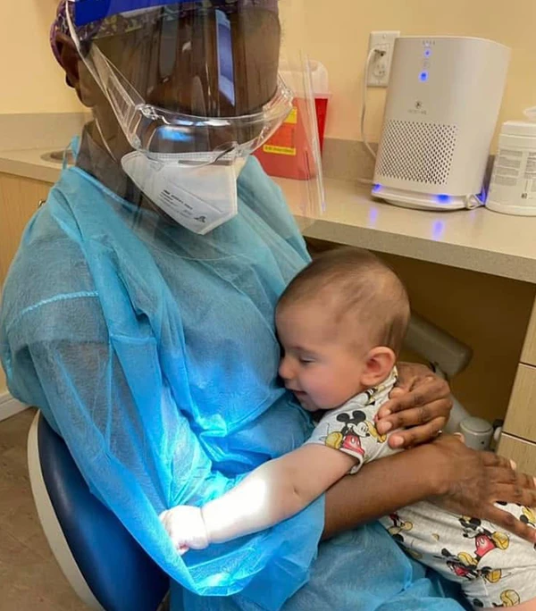 An infant sitting in Dr. Karan's lap hugging her during first visit.